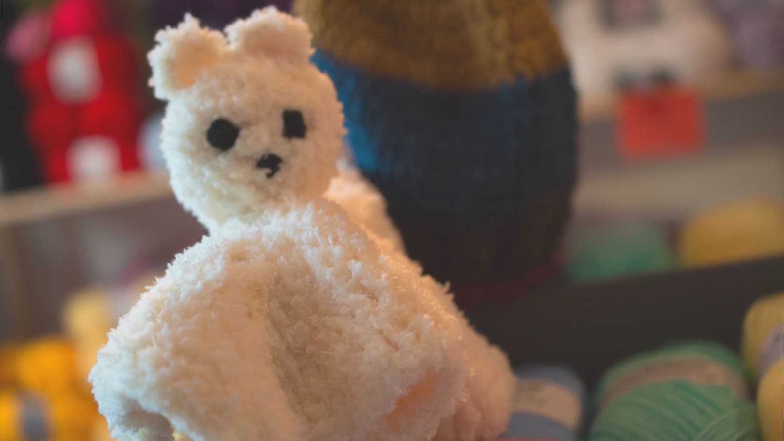 Doudou tricoté main devant les pelotes de la boutique